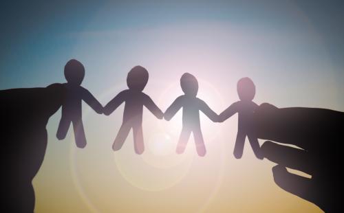 Paper chain of people held in the sunlight